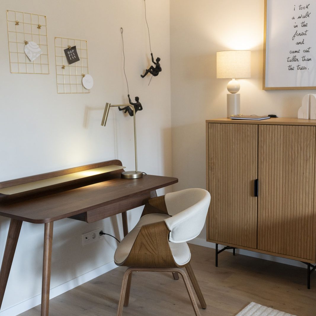 Arbeitsecke mit Holzschreibtisch, Stuhl, Lampe und Kommode in einer Ferienwohnung